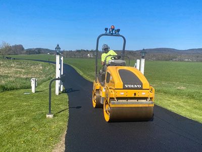 Over the Top employee rolling a freshly paved drive